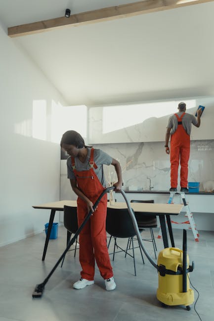 Two professional cleaners from Carpet Cleaning Haringey are preparing cleaning equipment from a white service van parked outside a modern residential building. The male cleaner, dressed in a red unifo